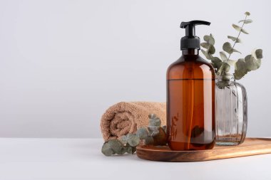 Banyo ve sağlık, sağlıklı yaşam için terry pamuk havlu ve kozmetik şişeyle dolu. Kahverengi şeffaf şeker şişesi, pamuk havlu ve okaliptüs..