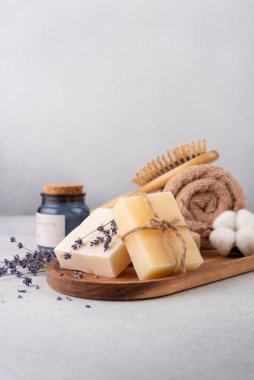 Ahşap tepside el yapımı sabun, havlu ve aroma mumu bulunan banyo malzemeleri. Çevre dostu ve sürdürülebilir yaşam tarzı için spa ve kişisel bakım organik ürünleri.