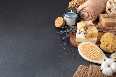 Ahşap tepside el yapımı sabun, havlu ve aroma mumu bulunan banyo malzemeleri. Çevre dostu ve sürdürülebilir yaşam tarzı için spa ve kişisel bakım organik ürünleri.