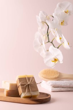 Bambu arka fırçası, el yapımı sabun çubukları ve ahşap tepside duran ve yanında narin bir orkide çiçeği bulunan doğal cilt bakımı ürünleri. Spa, sağlık ve güzellik kavramları için mükemmel..