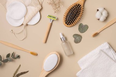 Tarafsız bir arkaplanda, bambu fırçası, jilet, cilt bakımı şişesi ve pamuk pedlerin yer aldığı çevre dostu güzellik gereksinimleri. Sağlık, kendine bakım ve sürdürülebilir yaşam tarzı temaları için mükemmel..