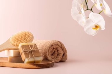 Bambu arka fırçası, el yapımı sabun çubukları ve ahşap tepside duran ve yanında narin bir orkide çiçeği bulunan doğal cilt bakımı ürünleri. Spa, sağlık ve güzellik kavramları için mükemmel..