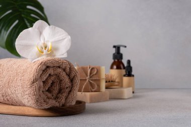 Sarılmış havlu, beyaz orkide, doğal sabun çubukları ve cilt bakım ürünleriyle lüks spa seti. Sağlık, rahatlama, güzellik ve çevre dostu cilt bakımı konuları için mükemmel..