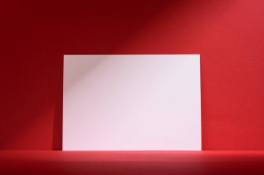 Kırmızı arka planda yumuşak gölgeler olan minimalist boş model poster. Ürün gösterisi, markalaşma ya da sanat gösterisi için mükemmel, basitliği, zarafeti ve modern tasarımı vurguluyor..