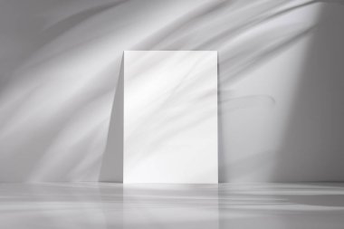Minimalist beyaz ya da gri arkaplan, boş beyaz bir poster, soyut ve modern bir kompozisyon için zıtlık ve gölge oyunu yaratıyor. Tasarım, sanat veya grafik sunum kavramları için ideal.