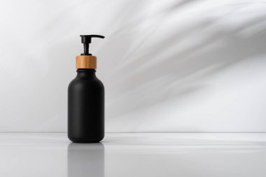 Bambu kapaklı siyah sabun makinesi yumuşak gölgeli arka planda minimalist tasarım. Çevre dostu, cilt bakımı ve sağlık teması için ideal. Temiz, modern banyo kavramları için mükemmel..