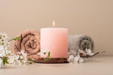 Mumları yakmak, spa odasındaki masaya aroma yaymak. Pastel renkli mumlar ve spa tedavisi için kiraz çiçeği dallarıyla güzel bir kompozisyon..