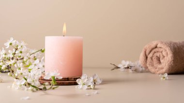 Mumları yakmak, spa odasındaki masaya aroma yaymak. Pastel renkli mumlar ve spa tedavisi için kiraz çiçeği dallarıyla güzel bir kompozisyon..
