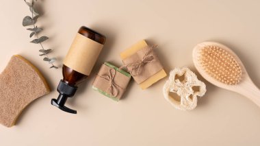 Bej arka planda sabun, fırça, luffa ve kehribar pompa şişesiyle doğal cilt bakımı gereklidir. Minimalist, çevre dostu, sağlıklı yaşam, hijyen ve sürdürülebilir yaşam tarzı kavramları.
