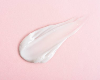 Açık pembe pastel arka planda kozmetik krem dokusu. 