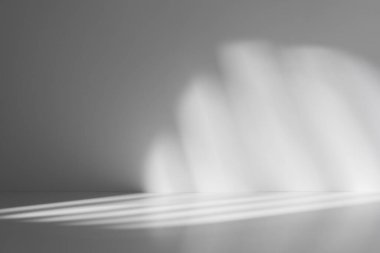 Yumuşak, soyut bir ışık deseni ve gölgeler pürüzsüz gri bir yüzey üzerinde, minimalist ve atmosferik bir zemin oluşturur..  