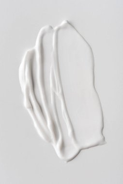 Tarafsız bir arkaplanda beyaz krem dokusu, pürüzsüz, parlak çizgiler ve doğal akış gösteriyor. Cilt bakımı, kozmetik ve güzellik konseptleri için mükemmel. Minimalist estetik.