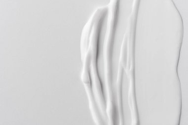 Tarafsız bir arkaplanda beyaz krem dokusu, pürüzsüz, parlak çizgiler ve doğal akış gösteriyor. Cilt bakımı, kozmetik ve güzellik konseptleri için mükemmel. Minimalist estetik.