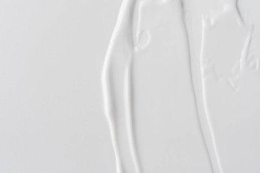 Tarafsız bir arkaplanda beyaz krem dokusu, pürüzsüz, parlak çizgiler ve doğal akış gösteriyor. Cilt bakımı, kozmetik ve güzellik konseptleri için mükemmel. Minimalist estetik.