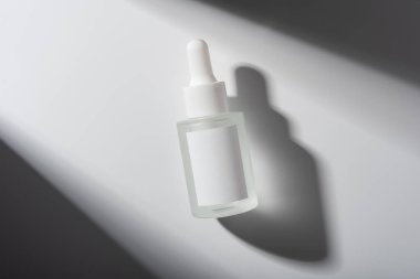 Boş etiketli minimalist cam damlalar ve temiz bir arkaplanda yumuşak gölgeler. Cilt bakımı, kozmetik, markalaşma veya lüks güzellik ürünleri için idealdir..