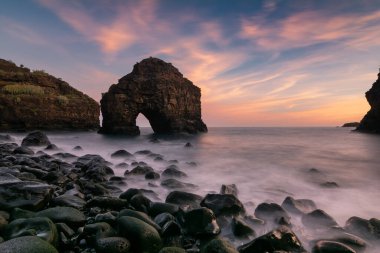 Gün batımında canlı gökyüzü, pürüzsüz dalgalar ve kayalık kıyı şeridi, Tenerife, Kanarya Adaları, İspanya. Seyahat, doğa ve manzara fotoğrafçılığı için mükemmel bir deniz manzarası..