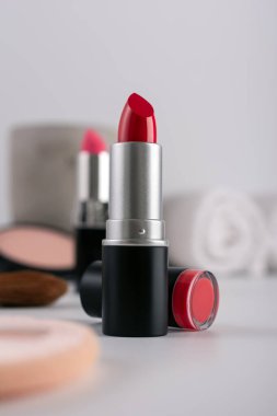 Dekoratif makyaj sehpası ve ön planda kırmızı ruj, seçici odaklanma. Güzellik ürünü ve makyaj konsepti.
