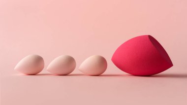 Makyaj süngeri pastel pembe tonlarda asgari arkaplanda. Güzellik, kozmetik ve cilt bakımı için mükemmel. Profesyonel reklamlar, ürün çekimleri ve kadın görselleri için ideal..
