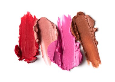 Kırmızı, pembe ve kahverengi tonlarda karışık ruj lekeleri ve parlak bir kaplama. Güzellik, moda ve makyaj kavramları için canlı ve sanatsal kozmetik örnekleri.
