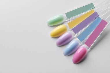 Pastel oje örnekleri yumuşak yeşil, sarı, leylak, mavi ve pembe arkaplanda. Farklı parlak renklerde tırnak uçları. Zarif ve enerjik güzellik konsepti.