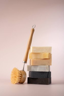 Pastel arka planda ahşap fırçalı el yapımı sabunlar, çevre dostu banyo kavramı..