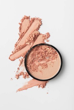 Kırık pembe allık tozunun beyaz zemin üzerinde dağınık parçacıklar olan üst görüntüsü. Kozmetik veya cilt tasarımı için minimal güzellik ürünü dokusu.