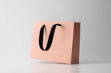 Açık arkaplanda siyah saplı pembe bir alışveriş çantasının minimalist maketi. Markalaşma, paketleme, tasarım sunumu veya çevrimiçi mağaza pazarlama görselleri için ideal.