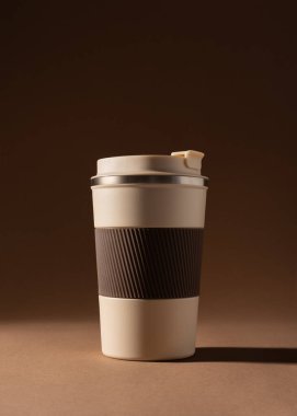 Yeniden kullanılabilir kahve fincanı, doğal gölgeli sıcak bej arka plan modeli. Markalaşma, paketleme, eko tasarım veya reklam için minimalist ürün şablonu. 
