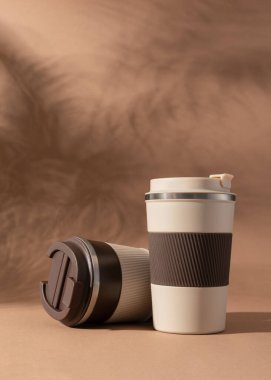 Yeniden kullanılabilir kahve fincanı, doğal gölgeli sıcak bej arka plan modeli. Markalaşma, paketleme, eko tasarım veya reklam için minimalist ürün şablonu. 