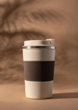 Yeniden kullanılabilir kahve fincanı, doğal gölgeli sıcak bej arka plan modeli. Markalaşma, paketleme, eko tasarım veya reklam için minimalist ürün şablonu. 