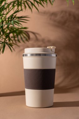 Yeniden kullanılabilir kahve fincanı, doğal gölgeli sıcak bej arka plan modeli. Markalaşma, paketleme, eko tasarım veya reklam için minimalist ürün şablonu. 