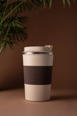 Yeniden kullanılabilir kahve fincanı, doğal gölgeli sıcak bej arka plan modeli. Markalaşma, paketleme, eko tasarım veya reklam için minimalist ürün şablonu. 