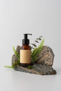 Taş podyumda yeşil yapraklı kozmetik pompa modeli. Boş etiketli doğal cilt bakımı ürünü marka şablonu. Organik ve çevre dostu güzellik temaları için minimalist kompozisyon.