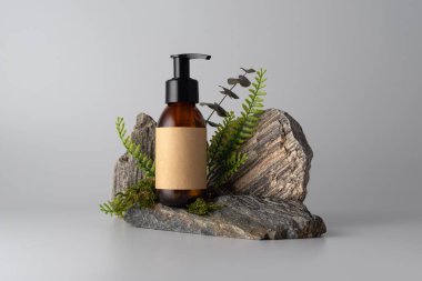 Taş podyumda yeşil yapraklı kozmetik pompa modeli. Boş etiketli doğal cilt bakımı ürünü marka şablonu. Organik ve çevre dostu güzellik temaları için minimalist kompozisyon.