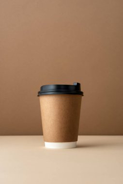 Tarafsız arka planda siyah plastik kapaklı kağıt kahve fincanı. Hazır içecekler, eko ambalajlar ya da cafe kimliği görselleri için en düşük markalaşma konsepti.