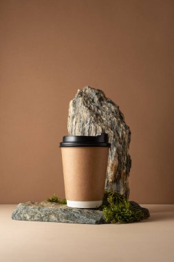Çevre dostu, siyah kapaklı, doğal taşlı ve yosun kaplı kahve fincanı. Sürdürülebilir içecek markası için minimalist maketler kahverengi arka planda markalaştırılıyor.