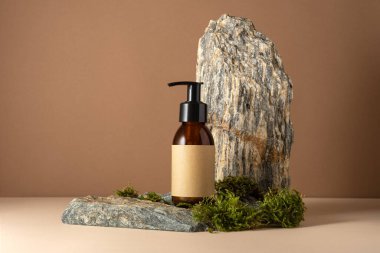 Minimum kehribar kozmetik şişe modeli, pompalı ve üzerinde taş ve yosun arkaplan etiketi olan boş bir kraft etiketi. Organik cilt bakımı, ekolojik ürün markalaşması ya da doğal güzellik sunumları için mükemmel..