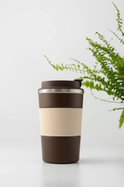 Hafif eğreltiotu üzerinde yeniden kullanılabilir termodinamik kahve bardağı. Çevre dostu, sürdürülebilirlik, doğaya duyarlı yaşam tarzı ve markalaşma modellemeleri için minimum tasarım konsepti.