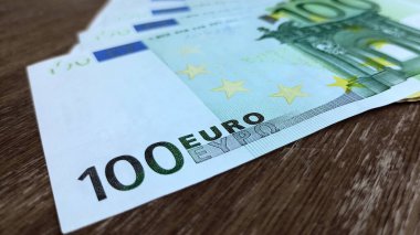 100 Euro 'nun fotoğrafını çek. Tahta masadaki 100 avroluk banknotun ön yüzü..