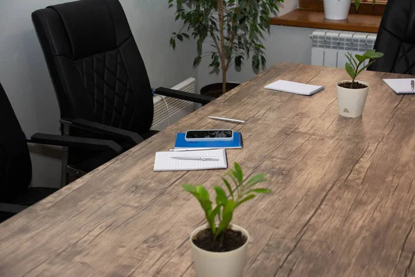 Ofiste, masanın üzerinde bir dizüstü bilgisayar, bir kalem, bir not defteri ve saksıda çiçekler var. Ofis masası. Tasarımcılar için herşey