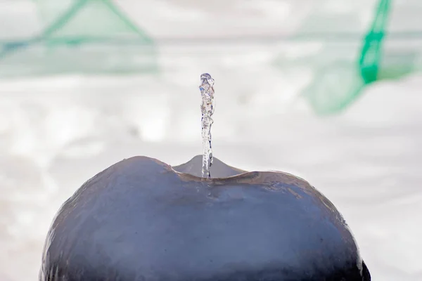A small fountain rises from the ice