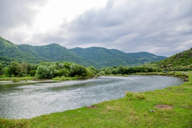 Göl ve büyük kaya. Güzel doğa, nehir yokuş aşağı akıyor. Yeşil ormanlar ve dağlar