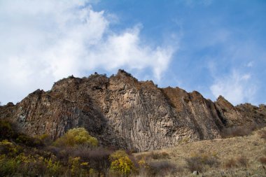 Dik uçurumlar ve altın ağaçlar. Sonbahar manzarası ve mavi gökyüzü