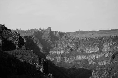 Dağlardaki kayalık bir uçurumun gri ölçekli görüntüsü.