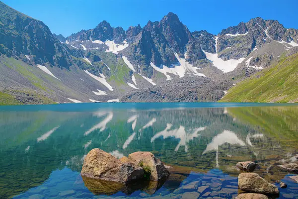 Yüksek kayalık dağları ve kristal berrak gölü olan güzel doğal manzara. Mavi göl. Mavi göl. Göllü güzel bir dağ. Yabani çiçekler