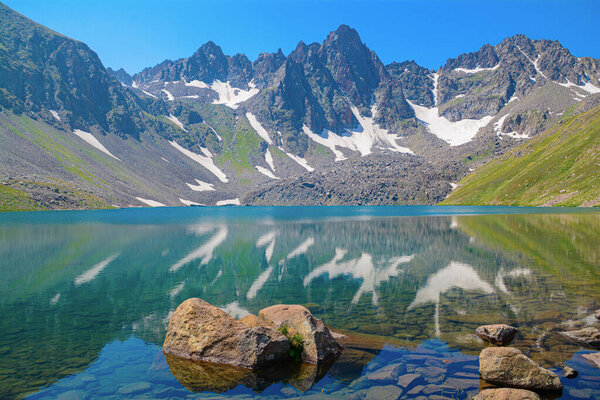 Красивый природный ландшафт с высокими скалистыми горами и кристально чистым озером. Голубая лагуна. Голубое озеро. Красивая гора с озером. Дикие цветы