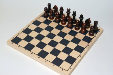 Beyaz bir masada siyah beyaz taşlarla satranç oyunu