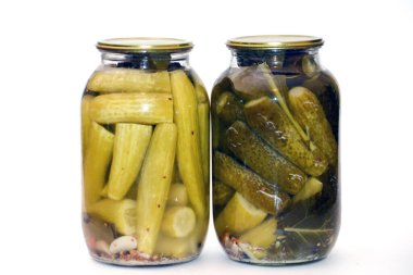 pickled green onions and cucumbers in glass jars isolated on white background.