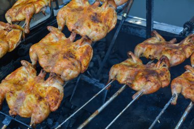 Izgarada tavuk pişirmek. Ateşin üstünde tavuk. Tavuk barbeküsü. Bir restoranda fırında kızarmış tavuk, fotoğrafa yakın çekim. Dumanın içinde ızgara tavuk. Fast food