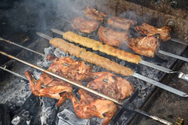 Tavuklu barbekü, şiş kebap ve domuz eti. Barbeküde yemek pişirmek. Izgarada et pişirme süreci. Barbeküde ızgara et ve şiş.